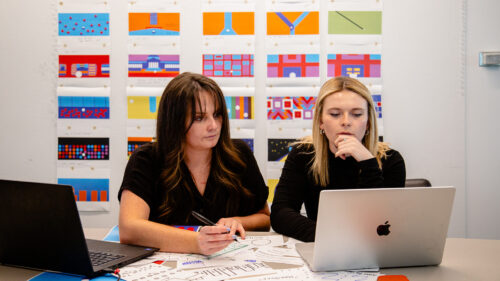 Two Perkins&Will designers reviewing digital art concepts for “Currents of Chicago” installation at ART on THE MART ahead of NeoCon 2025.