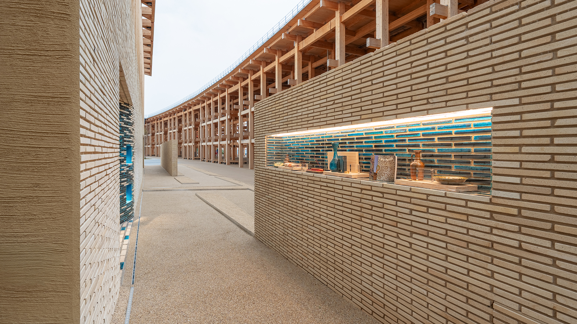 Side view of pavilion wall with narrow display window showcasing Uzbek ceramics and textiles.