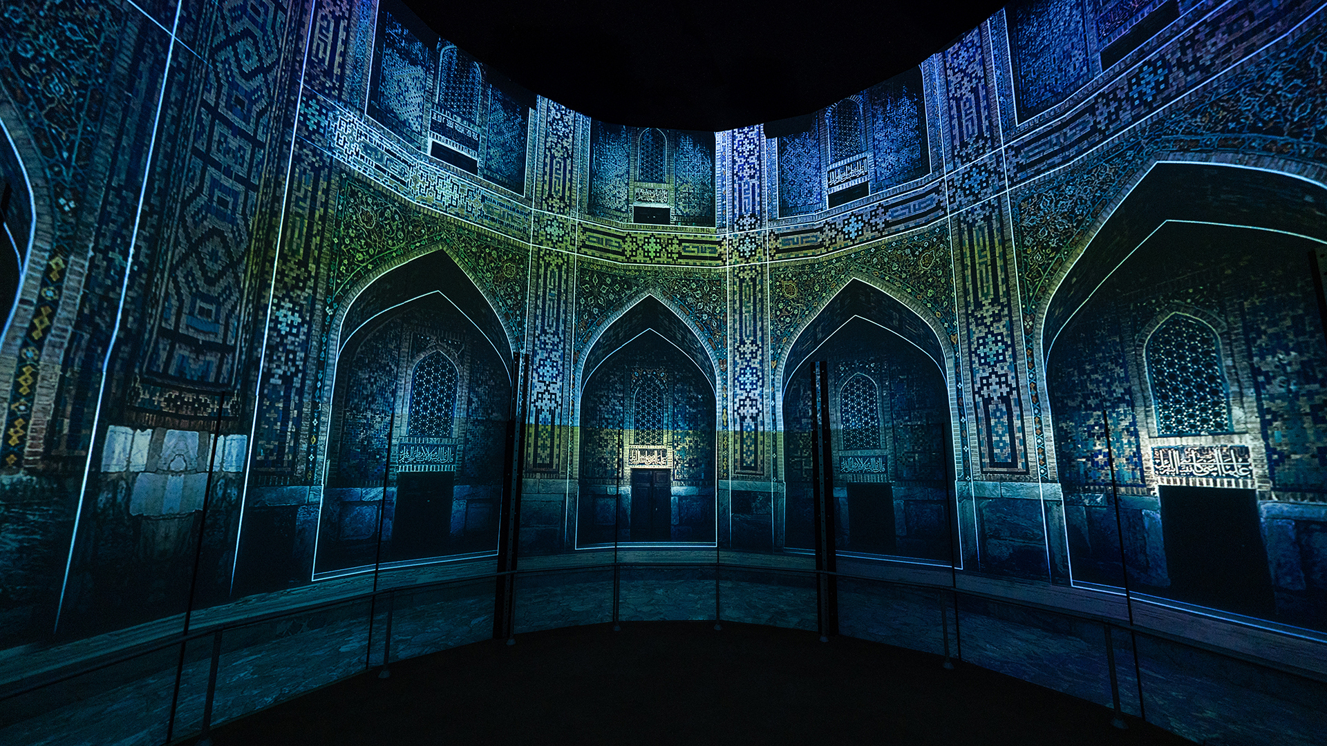 Panoramic interior projection of richly patterned Islamic architecture surrounding a circular space.
